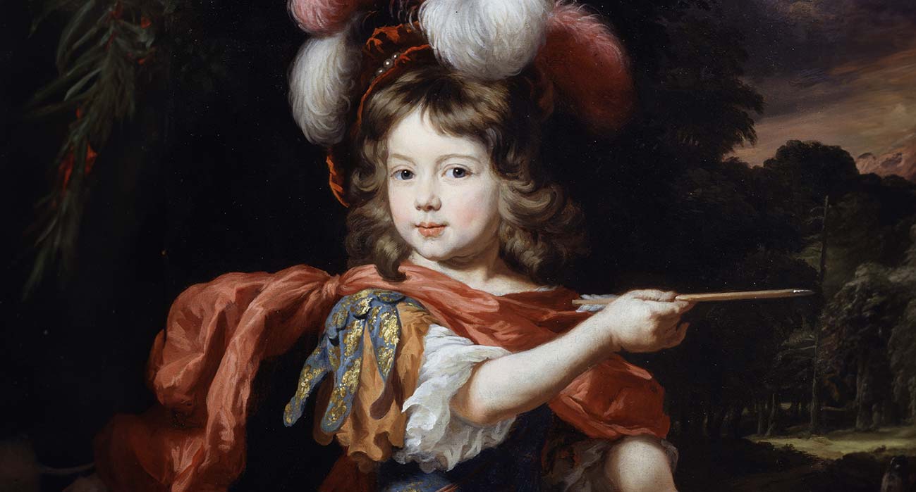 Junge in barockem Kostüm mit blau-goldenem Ärmel, rotem Umhang und Federhut, der mit einem Stab auf eine Landschaft zeigt.