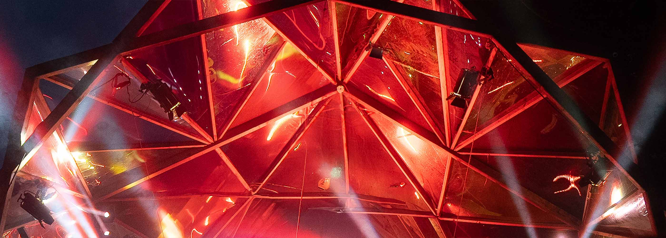 Rotes Veranstaltungszelt mit geometrischem Dach, beleuchtet und Teil der MS Dockville x HaspaJoker Kooperation.