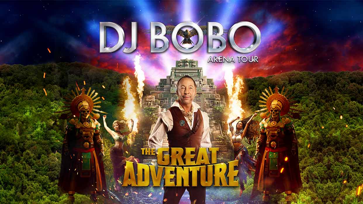 DJ Bobo steht vor einer Pyramide mit Flammen und wird von vier Personen in farbenfrohen, aztekisch inspirierten Kostümen flankiert, darüber der Schriftzug 'DJ BOBO ARENA TOUR' und darunter 'THE GREAT ADVENTURE'