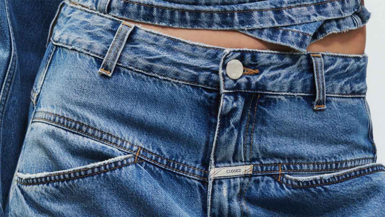 Blaue Jeanshose mit Knopfverschluss und sichtbarem Markenlabel 'Closed' am Bund.