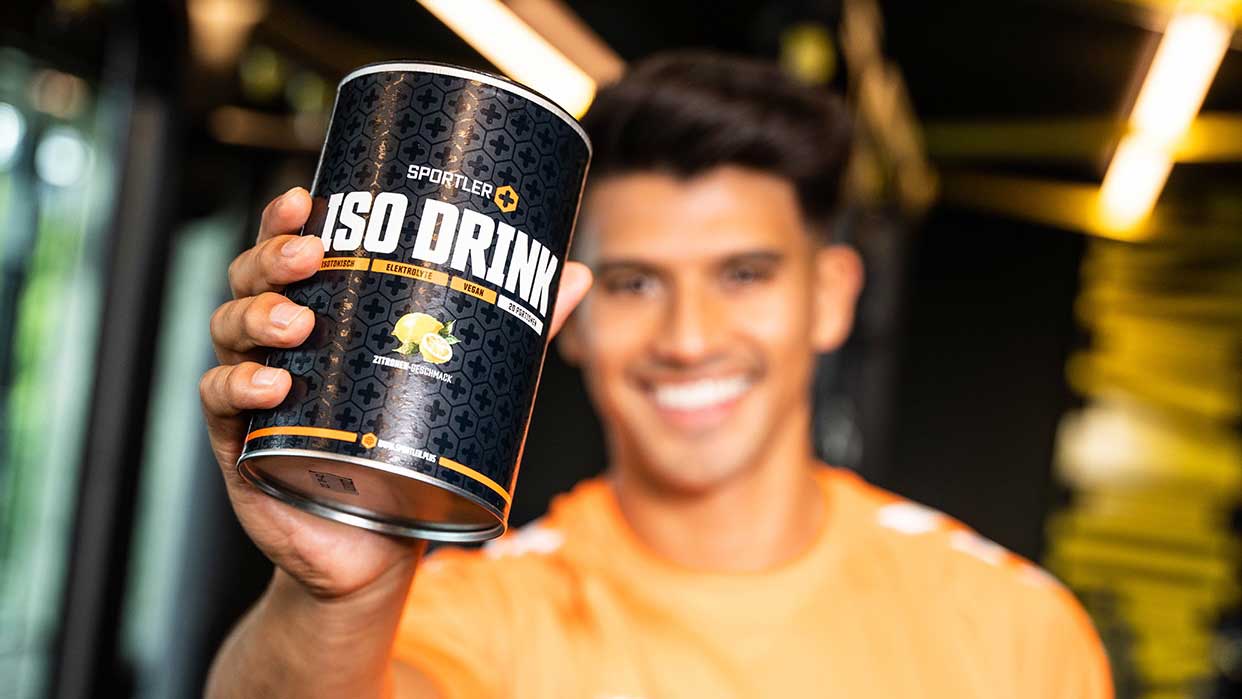 Hand hält Dose mit der Aufschrift 'SPORTLER ISO Drink' in Schwarz mit gelben Akzenten.