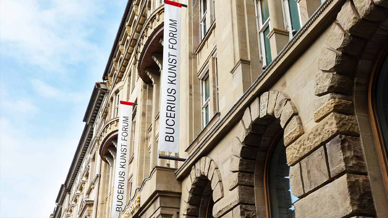 Fassade des Bucerius Kunst Forums in Hamburg mit weißen Bannern und historischen Sandsteinbögen.