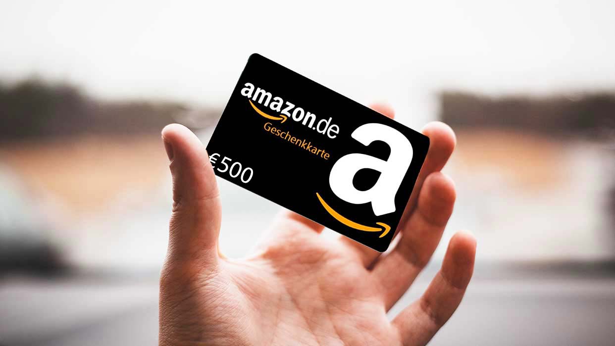 Hand hält eine schwarze Amazon.de Geschenkkarte im Wert von 500 Euro.